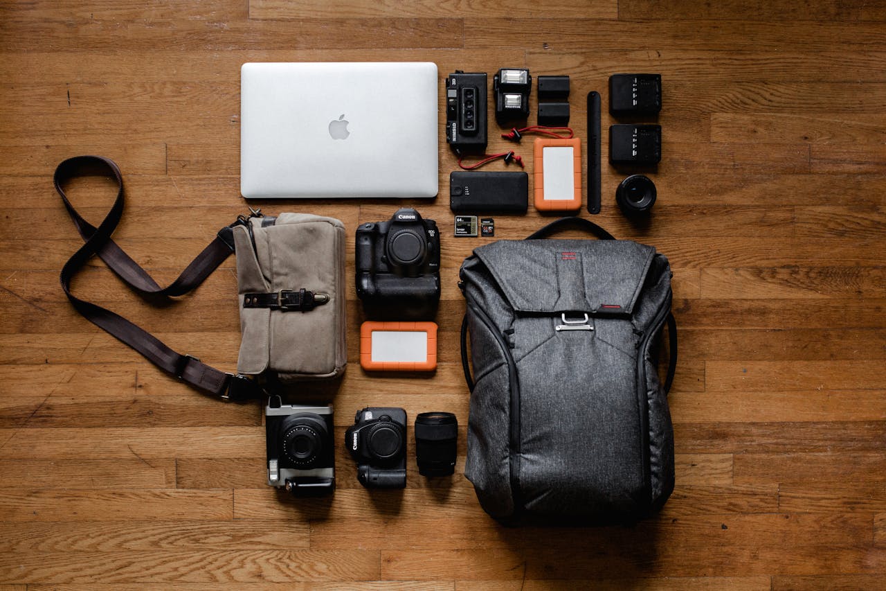 High-angle shot of camera equipment and laptop arranged on wooden floor for photography setup.